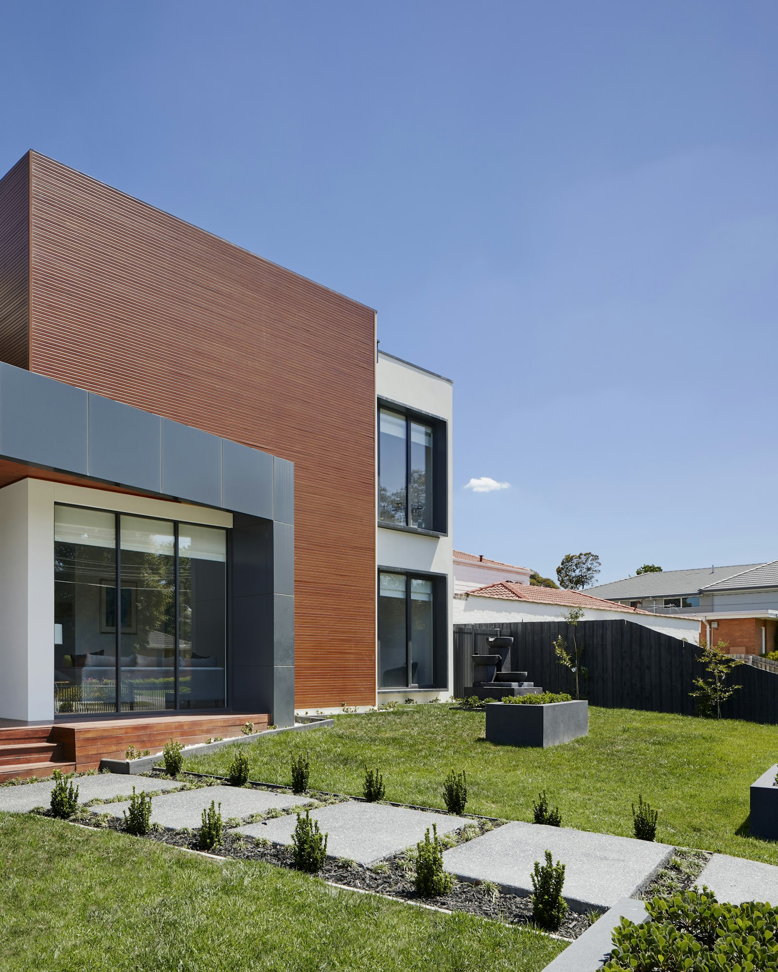 Wood-clad architecture with stepping-stone paving through the garden.
