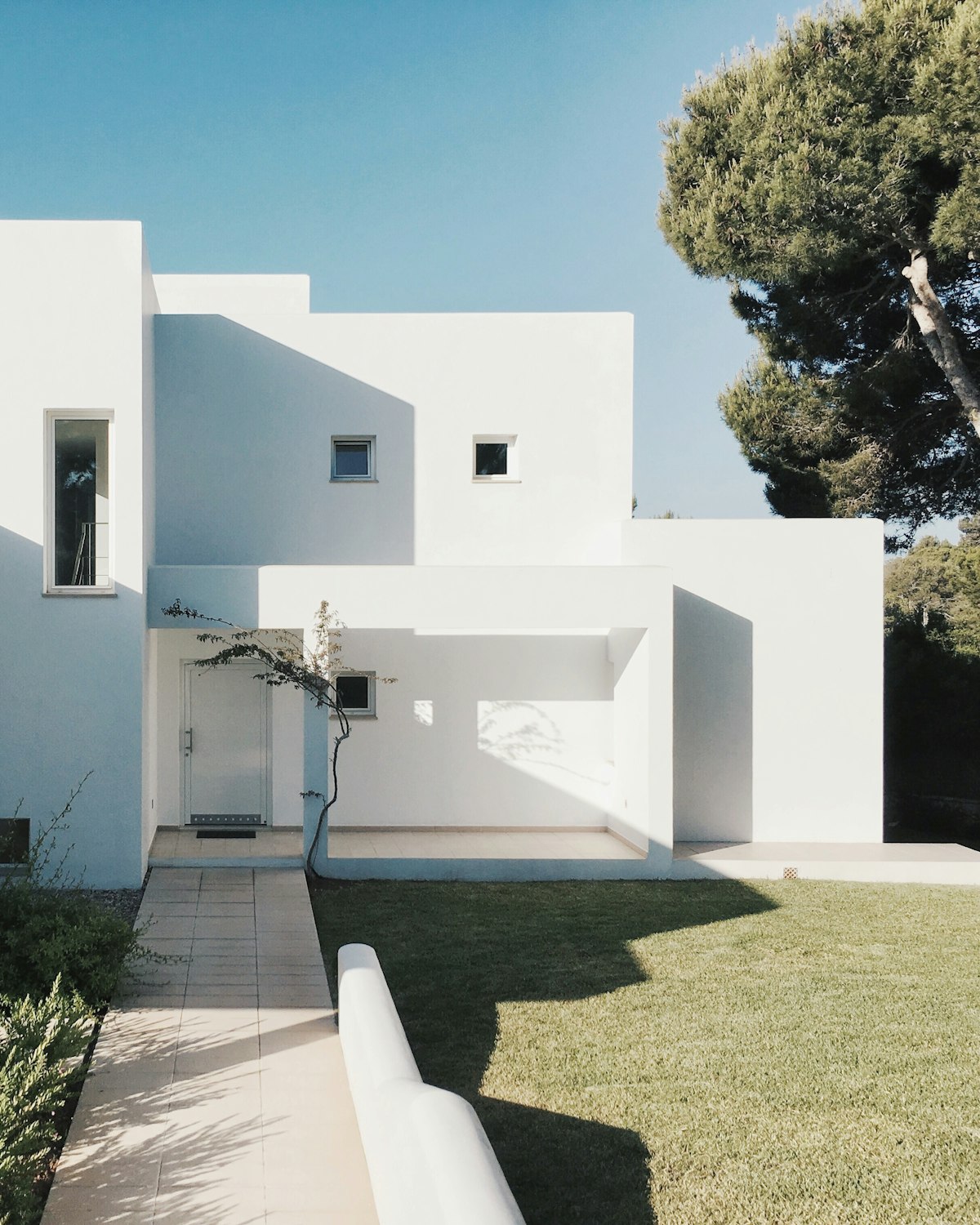 Minimalist facade with a paved entry path and lawn.
