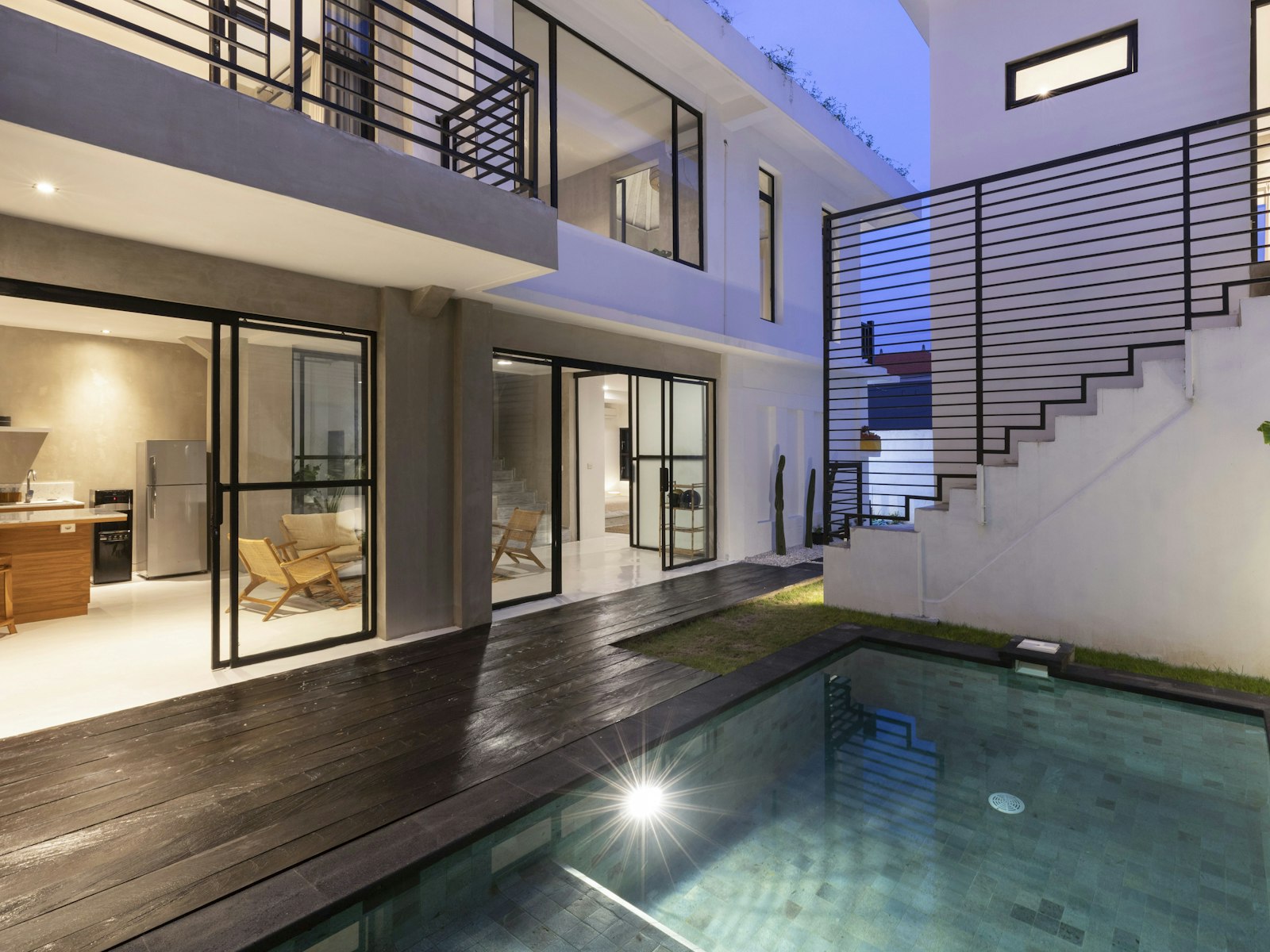 Timber deck and pool terrace lit for evening use beside guest rooms.